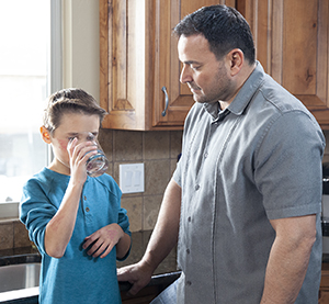 Man giving boy glass of water.
