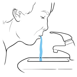 Person spitting water  into sink.