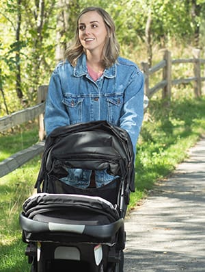 Person walking outdoors with baby in stroller.