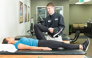 Physical therapist working with person on leg stretches.