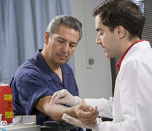 Healthcare provider taking blood from man's arm.