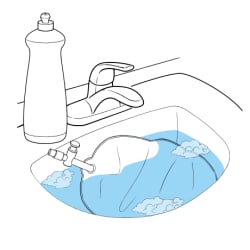 Catheter bag in sink full of soapy water.