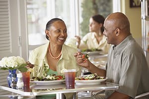 Man and woman sitting in a restaurant eating salads.