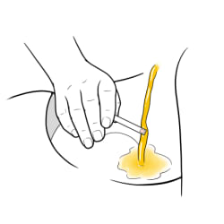 Hand dipping ketone test strip into stream of urine.