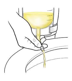 Closeup of hand holding tube on urinary catheter bag, draining urine into toilet.