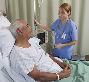 Healthcare provider caring for a patient in hospital bed.