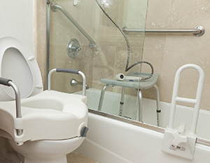 Bathroom set up with grab bars, raised toilet seat, and other safety features.