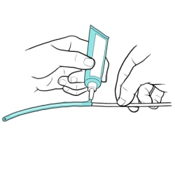 Person holding catheter tip and applying water-based lubricant on first 2 to 6 inches.