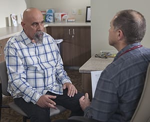 Man talking to doctor in exam room.