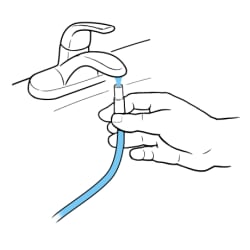 Hand holding opening of catheter tube under faucet with running water filling tube.